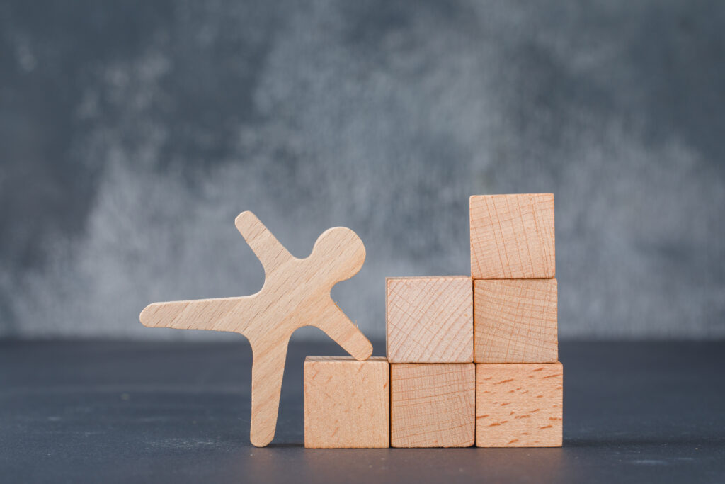conceptual of business with wooden blocks like stairs with wooden human figure on dark color background side view. space for text horizontal image