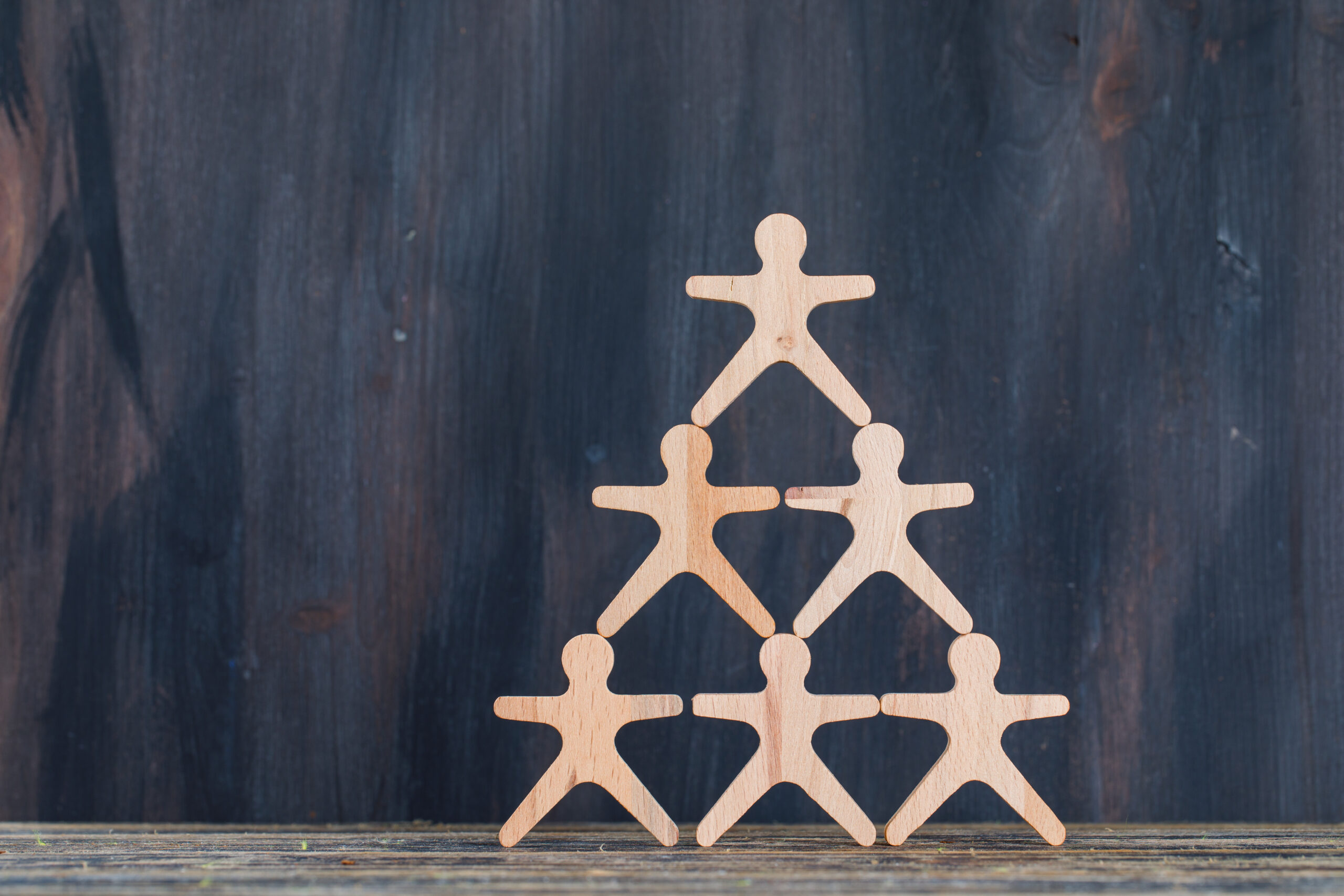 marketing and customer management concept with wooden figures on wooden and grunge background side view.
